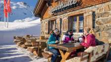 Trois amies savourent un café sur la terrasse ensoleillée de la cabane Grueb