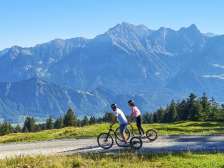 Deux personnes descendent la vallée en scooter alpin avec, en arrière-plan, les montagnes de la Bündner Herrschaft .