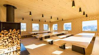 Salle de séjour d'un logement de groupe avec grandes tables et cheminée