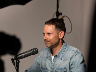 L'animateur Manuel Rothmund devant le microphone du podcast L'animateur Manuel Rothmund est assis devant le microphone du podcast dans le studio de podcasting