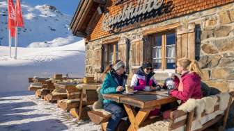 Trois amies savourent un café sur la terrasse ensoleillée de la cabane Grueb